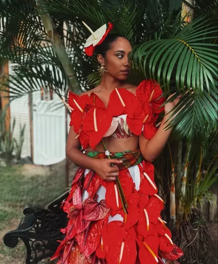 A woman in an anthurium-inspired red floral outfit posed among palms at the Jazz & Arts festival