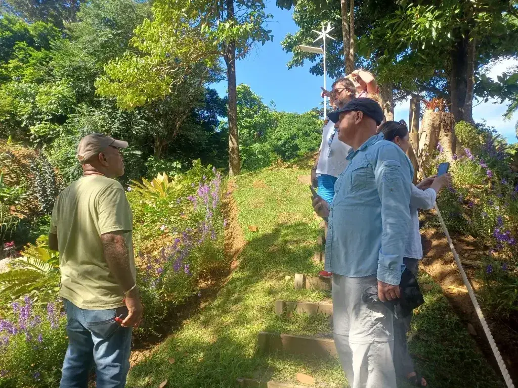 A guide leading visitors up a hillside trail through lush tropical gardens at Paradise Valley