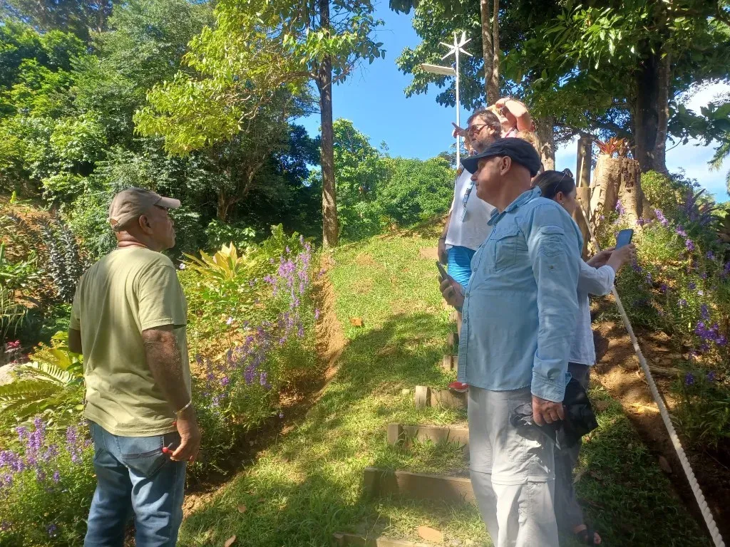 A guide leading visitors up a hillside trail through lush tropical gardens at Paradise Valley
