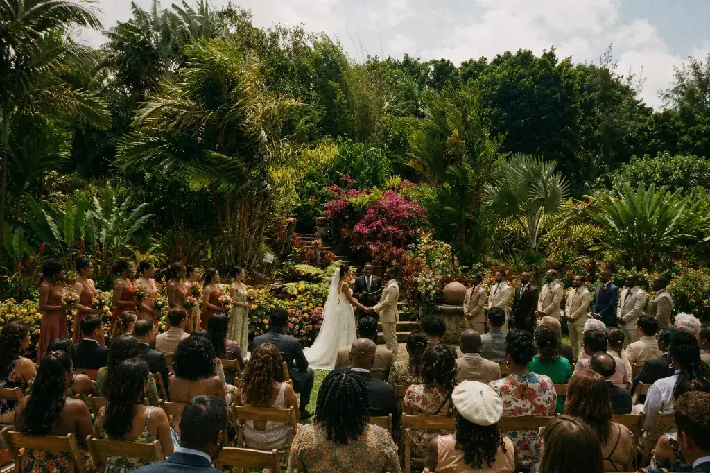 An outdoor wedding ceremony in a lush tropical garden at Paradise Valley, with the bride and groom surrounded by wedding party and seated guests